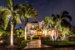 View of a Mediterranean-style home, enhanced by strategic lighting that accentuates its architectural beauty and creates a welcoming ambiance in the circular driveway.